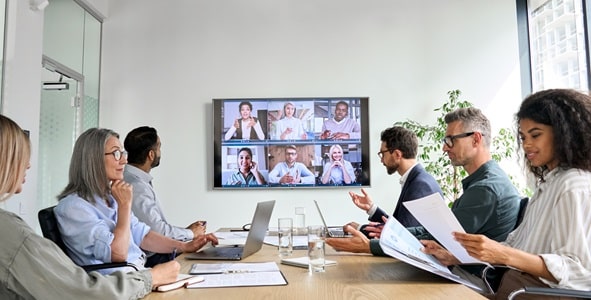 A group of employees sitting in a room and gathered around a conference table.