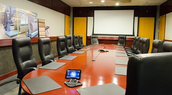 A large conference table that features a large projector screen.